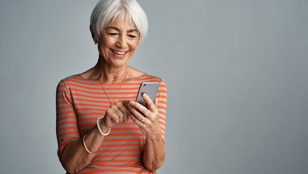 An older lady smiling while interacting with her phone